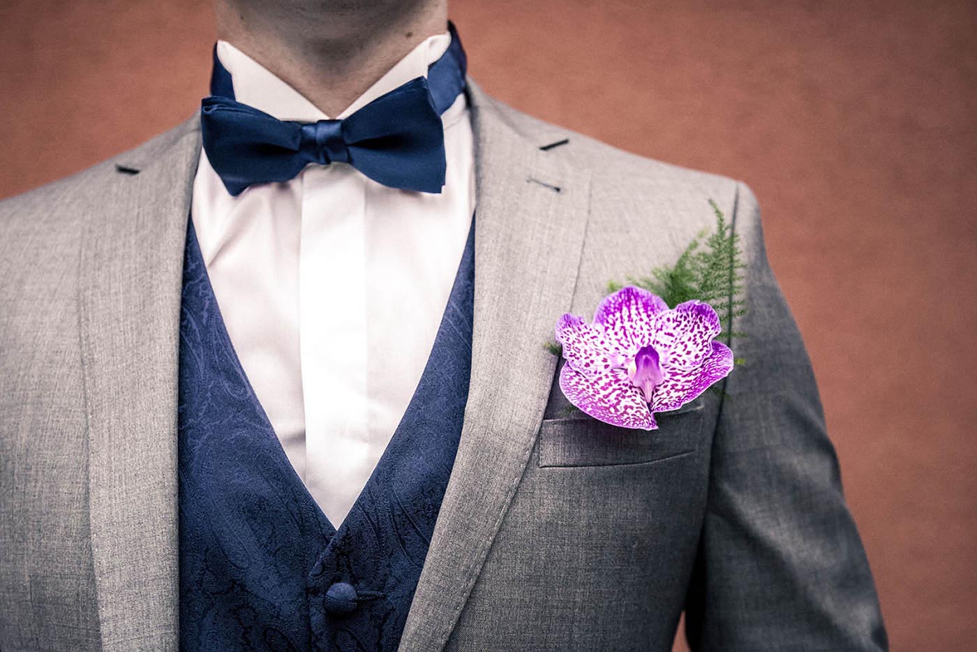 Le détail de la boutonnière du marié : une magnifique orchidée fushia