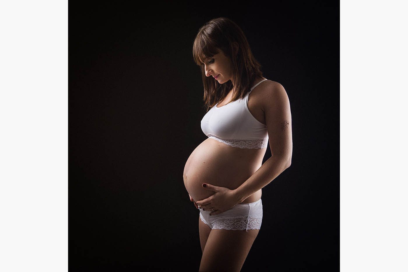 On découvre la belle silhouette de cette future maman qui pose en regadant tendrement son ventre arrondi